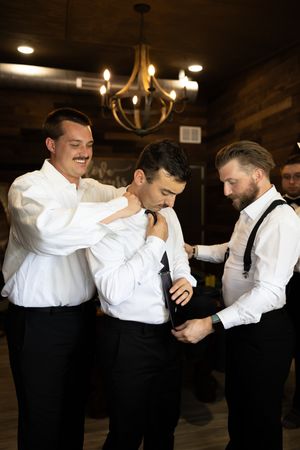 Orlando luxury wedding photographer groomsmen helping the groom with his tie.