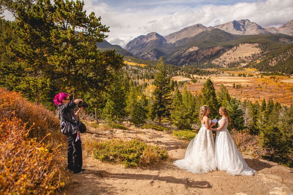 Wedding photographer capturing LGBTQ+ couple's portraits in scenic Rocky mountain National Park setting with fall colors.