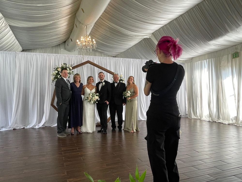 Wedding photographer with pink hair captures a ceremony inside an elegant white draped tent venue at The Wellshire Inn Event Center.