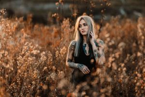 Artistic portrait surrounded by tall golden grass during autumn sunset.