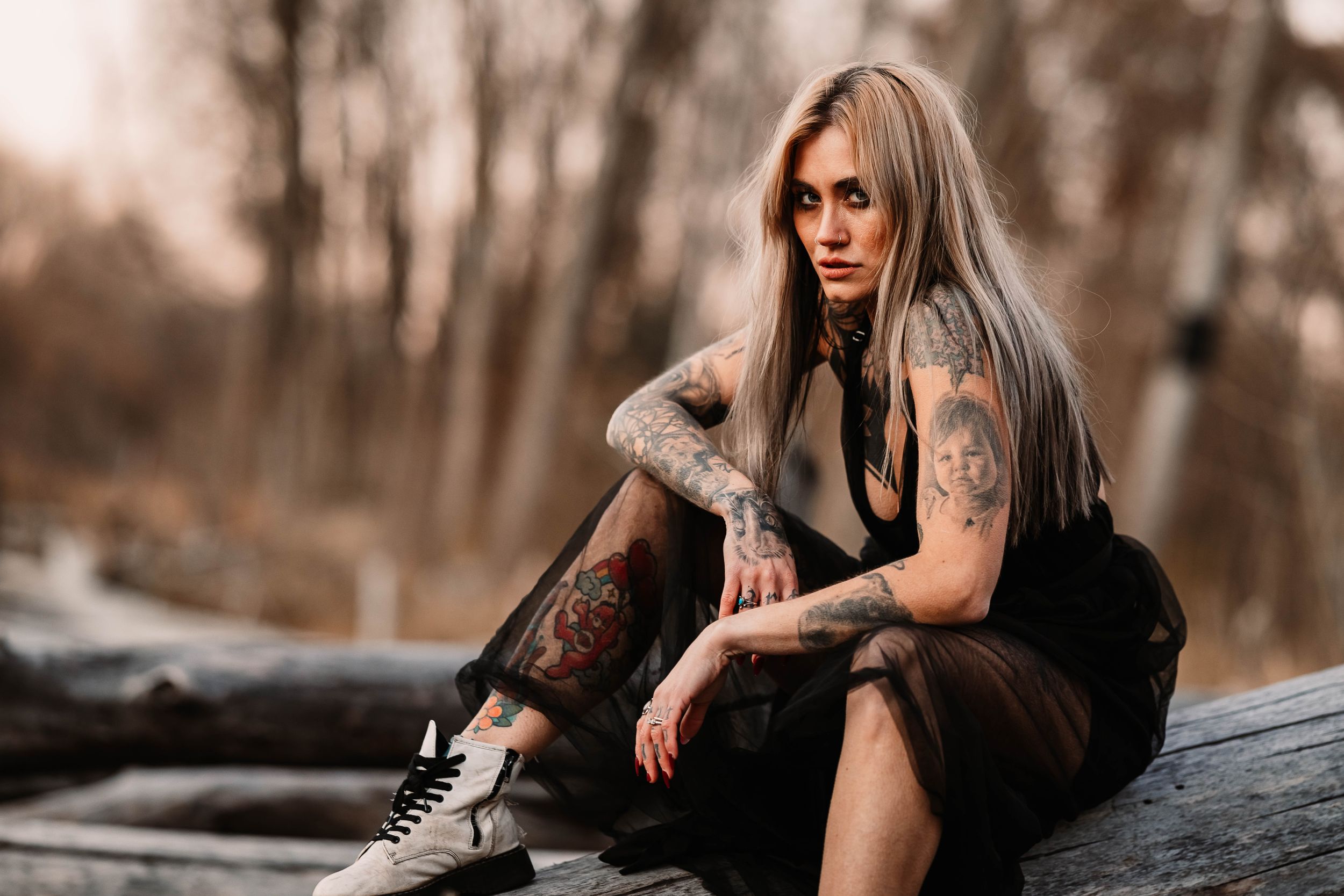 Moody portrait on weathered logs featuring dark vintage-inspired fashion.