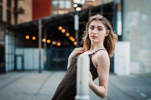 Urban fashion portrait with modern architecture and city lights in background.