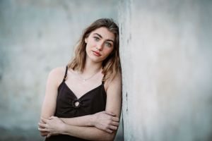 Moody portrait against concrete wall in black slip dress with natural lighting.