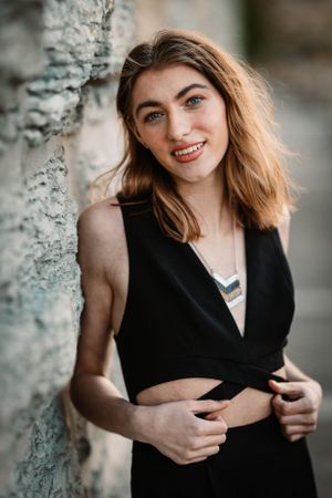 Portrait against stone wall showcasing black wrap top with natural lighting.
