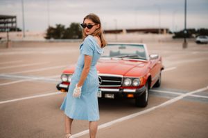Vintage scene with light blue dress and classic red convertible car.