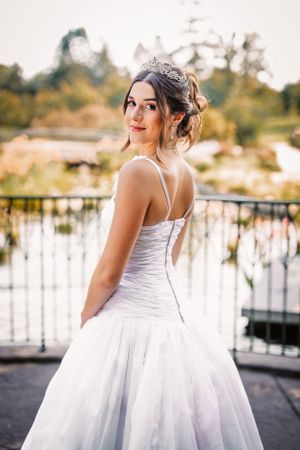 Elegant white wedding dress with fitted bodice and full skirt against a scenic outdoor backdrop.