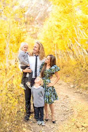 Family poses on mountain trail surrounded by bright yellow fall aspen trees at White Pine Campground.