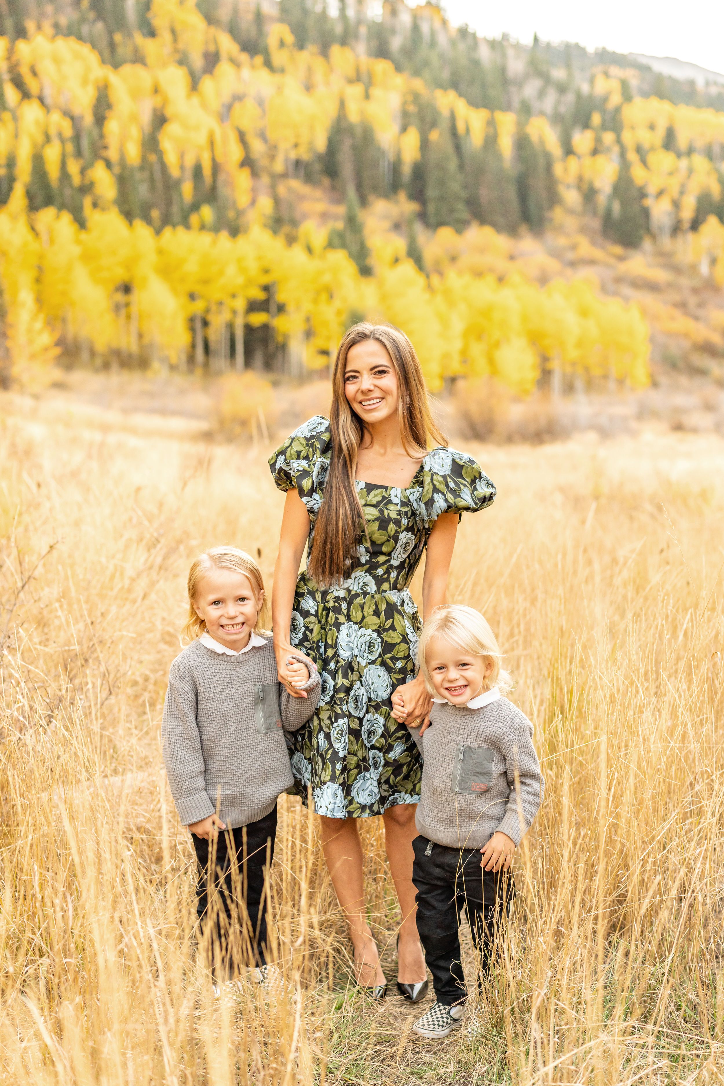 Family members stand together in tall golden grass with autumn mountain scenery behind them at White Pine Campground.