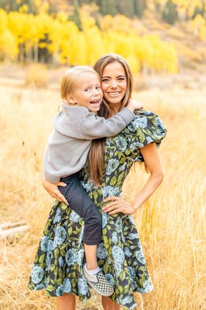 Mom and child share a loving moment against a backdrop of golden autumn aspen trees in Alta Canyon.