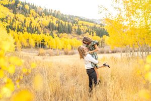 A couple in a golden autumn field with aspen trees and mountains in the background at White Pine Campground.