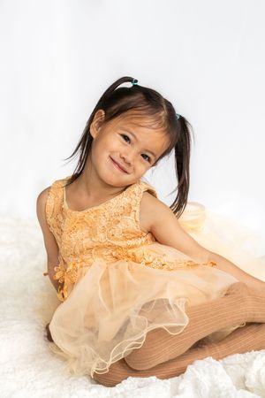 Toddler wearing princess dress posing on the ground in studio in Saratoga Springs.