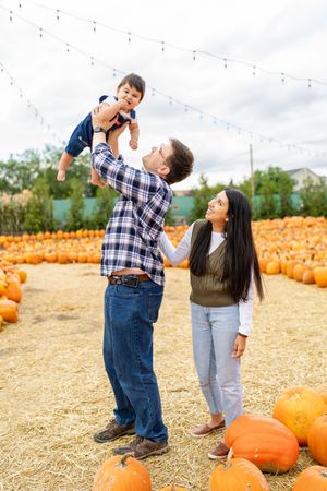 Dad holding up his little boy with mom at Kuwahara's pumpkin patch.