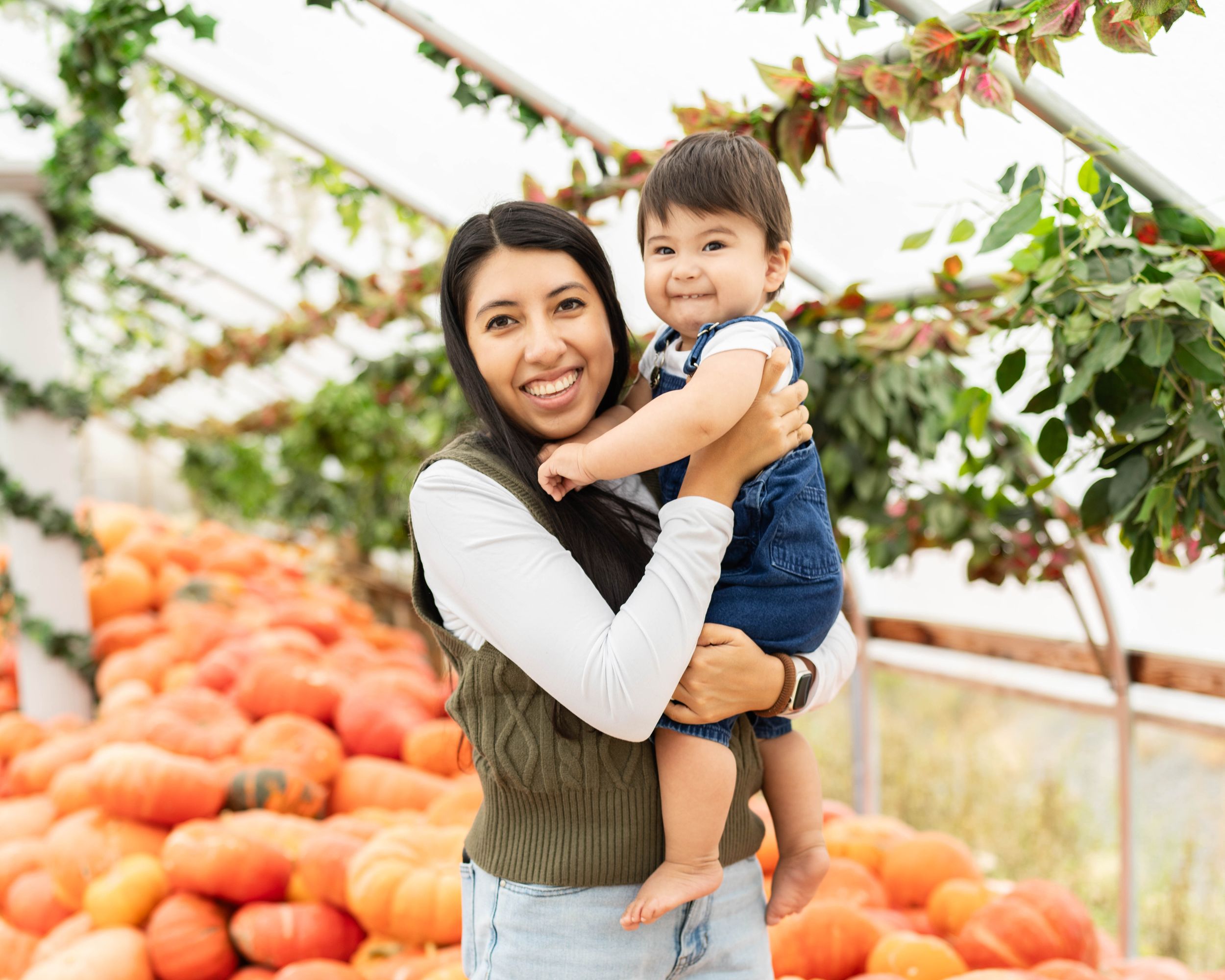 mom holding her toddler boy at Kuwahara's pumpkin patch indoors.