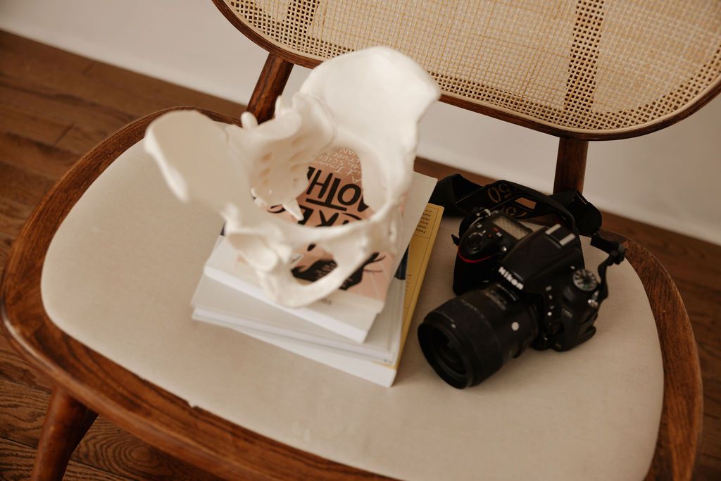 a pelvis model on top of a few doula books with a DSLR camera atop a chair