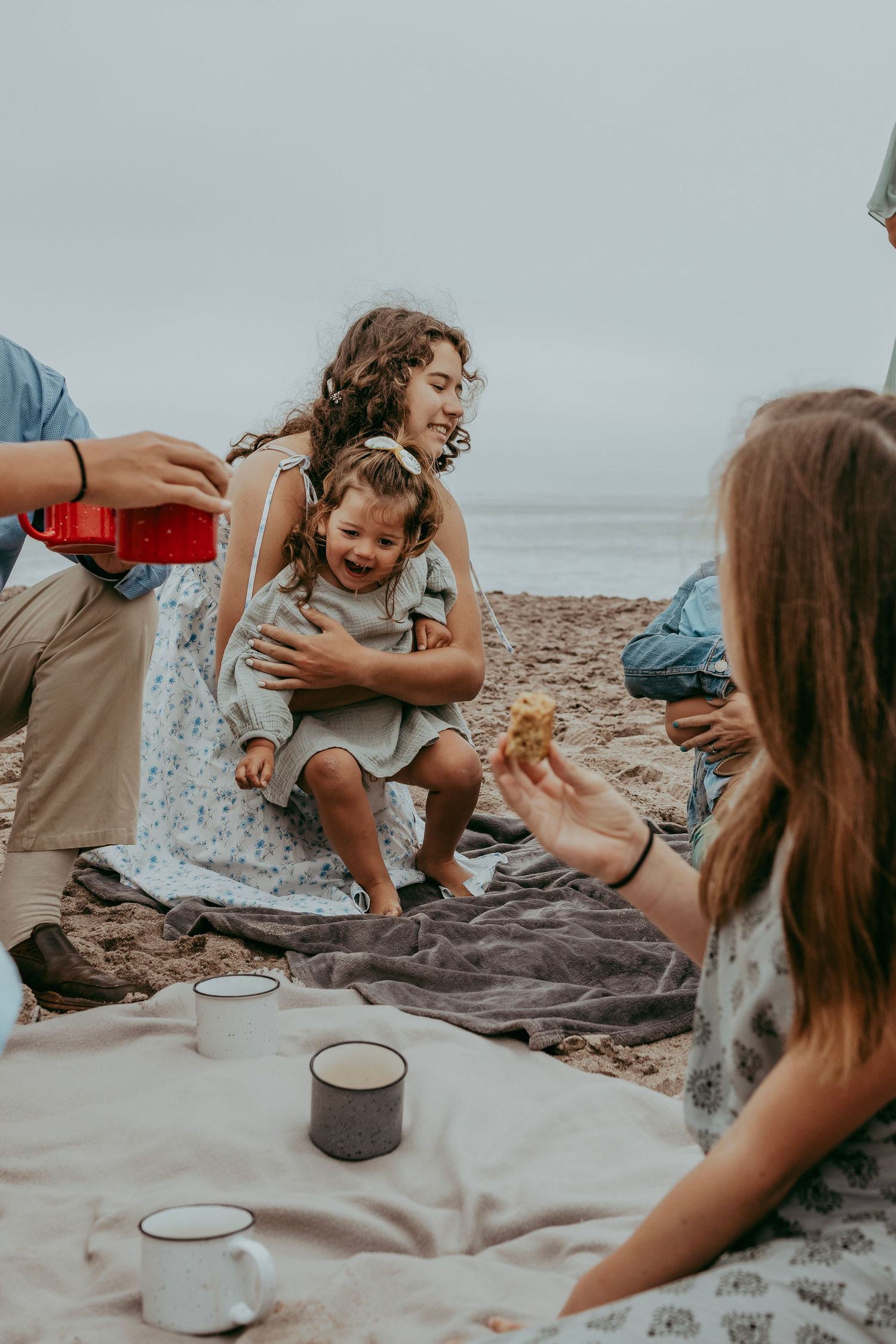 A family enjoying a joyful picnic on the beach in Swakopmund, laughing and having fun with the ocean and sandy shore