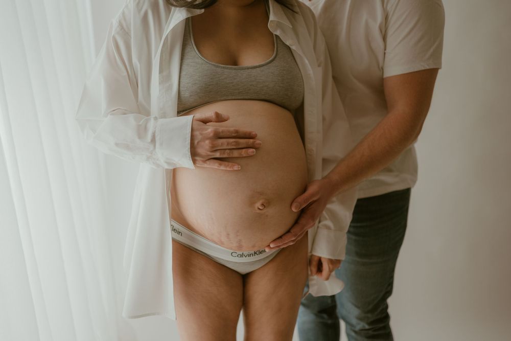 Pregnant belly with mom and dad's hands embracing baby bump. Studio in Clarksville, Tennessee. Photo by Disney Magic Photography.