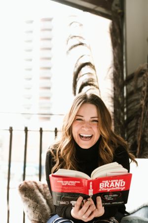 Woman reading book laughing. Photo by Samantha Bateman.