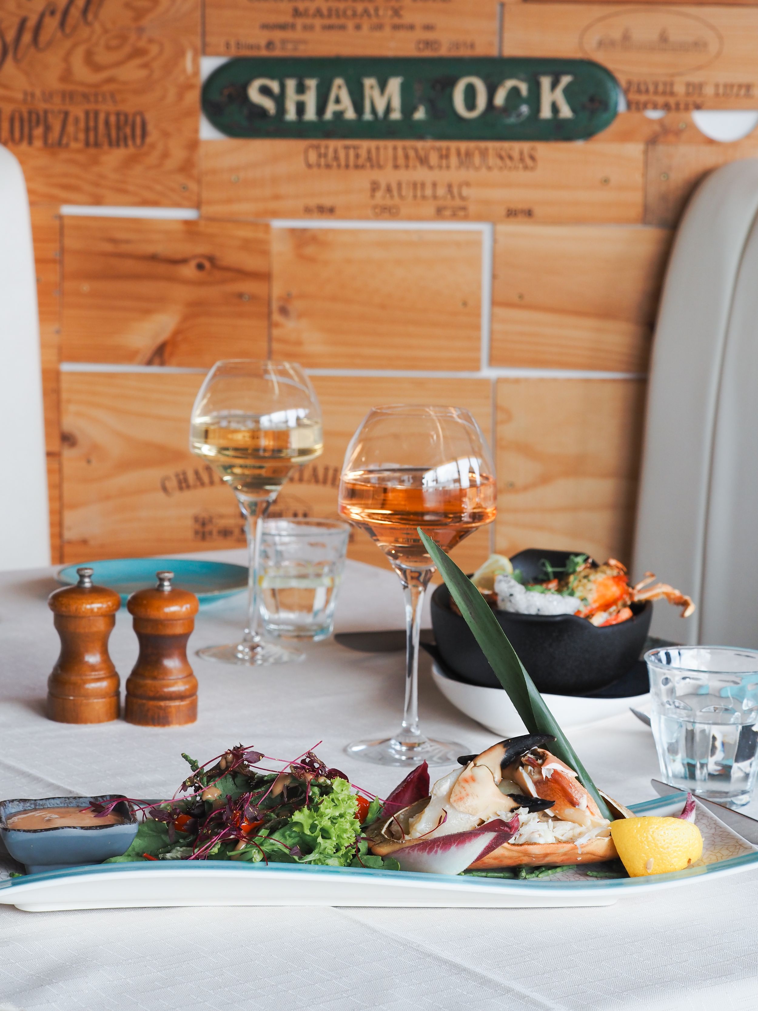 Fine dining seafood platter with wine glasses and wooden wine crate decor against a rustic background.