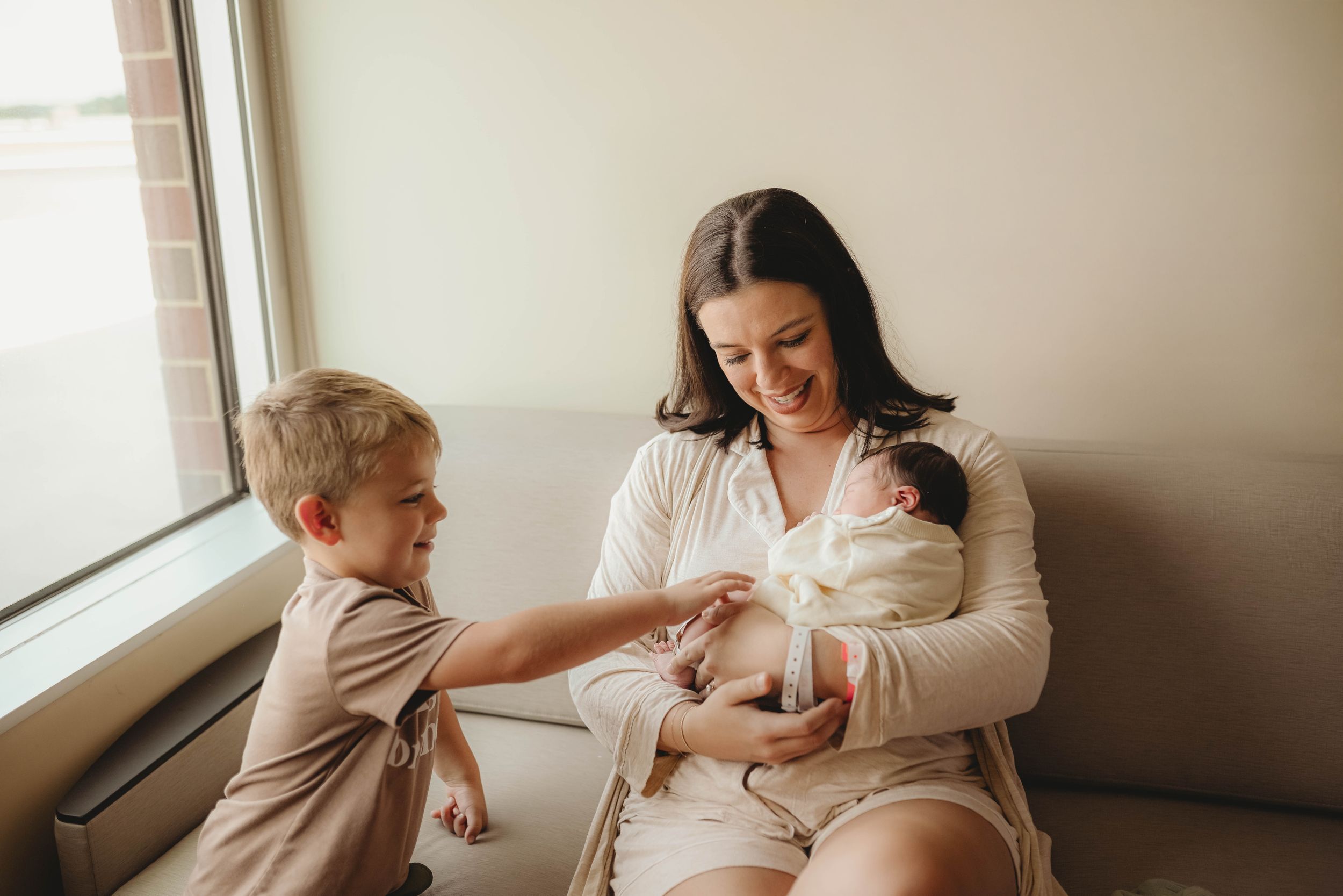 Family bonding moment on white couch in natural window light.