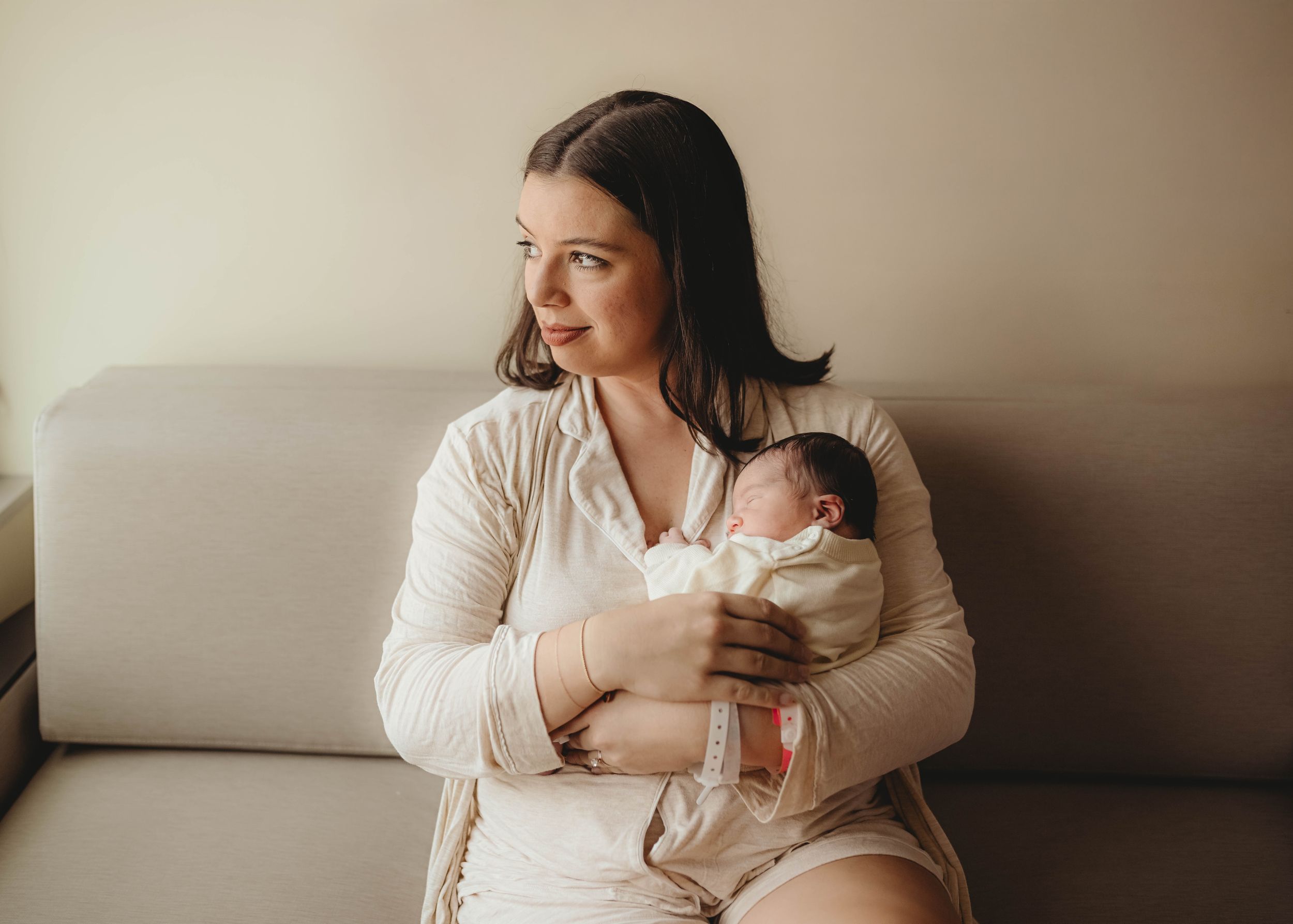 Tender family moment captured in soft neutral tones by window.