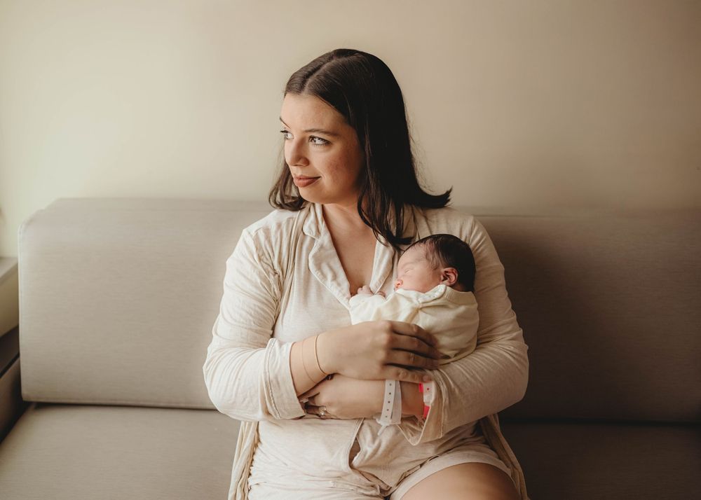 Tender family moment captured in soft neutral tones by window.