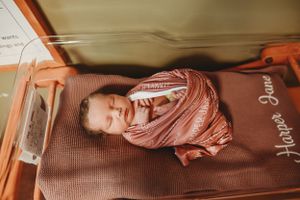 Professional newborn photography with baby on brown textured blanket.