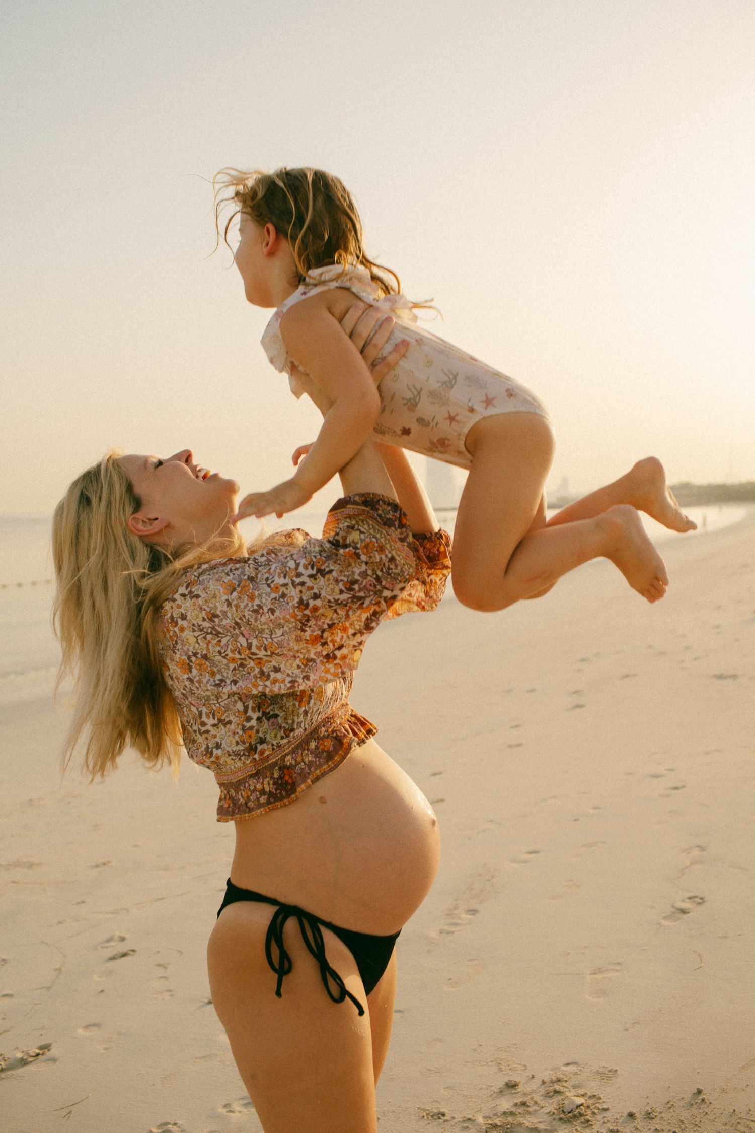 Heartfelt maternity beach session at sunrise in Sydney & Northern Beaches, featuring a mom, dad, and toddler sharing playful and loving fami