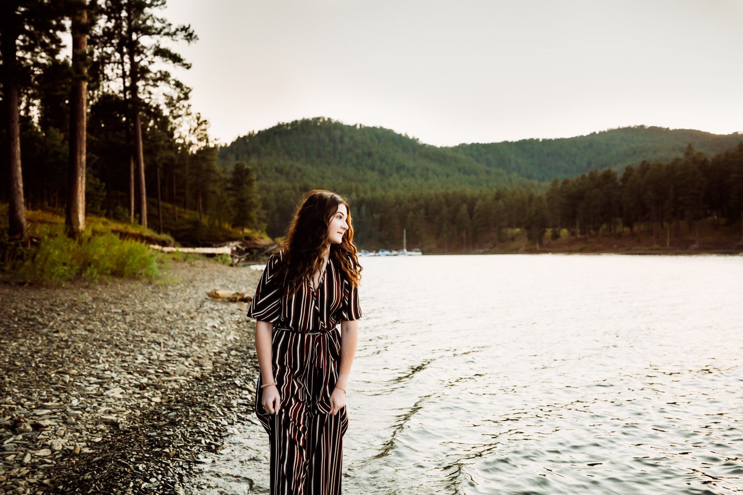 Senior girl in black jumpsuit looks out at lake in South Dakota