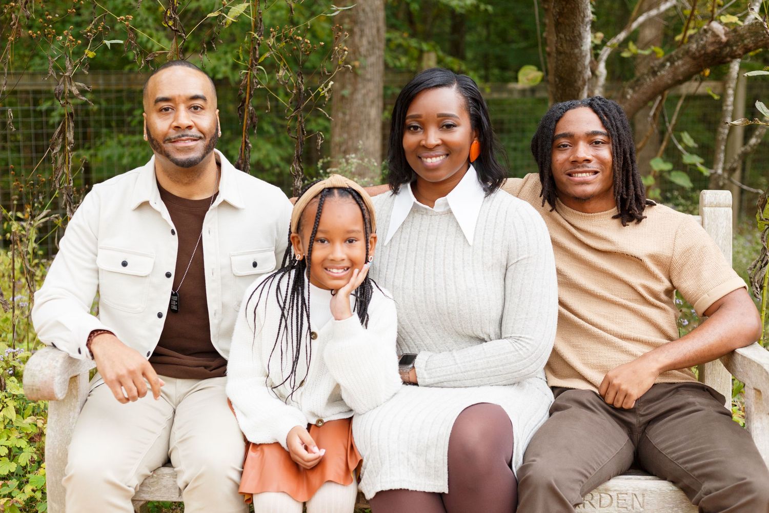 A group wearing coordinated white and brown outfits poses together outdoors in a natural setting.