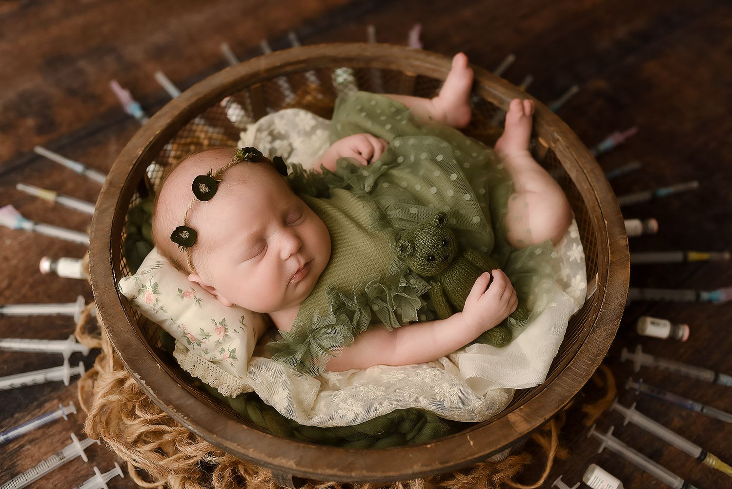 Sleeping newborn baby in heart-shaped basket with teddy bear on soft cream fur backdrop.