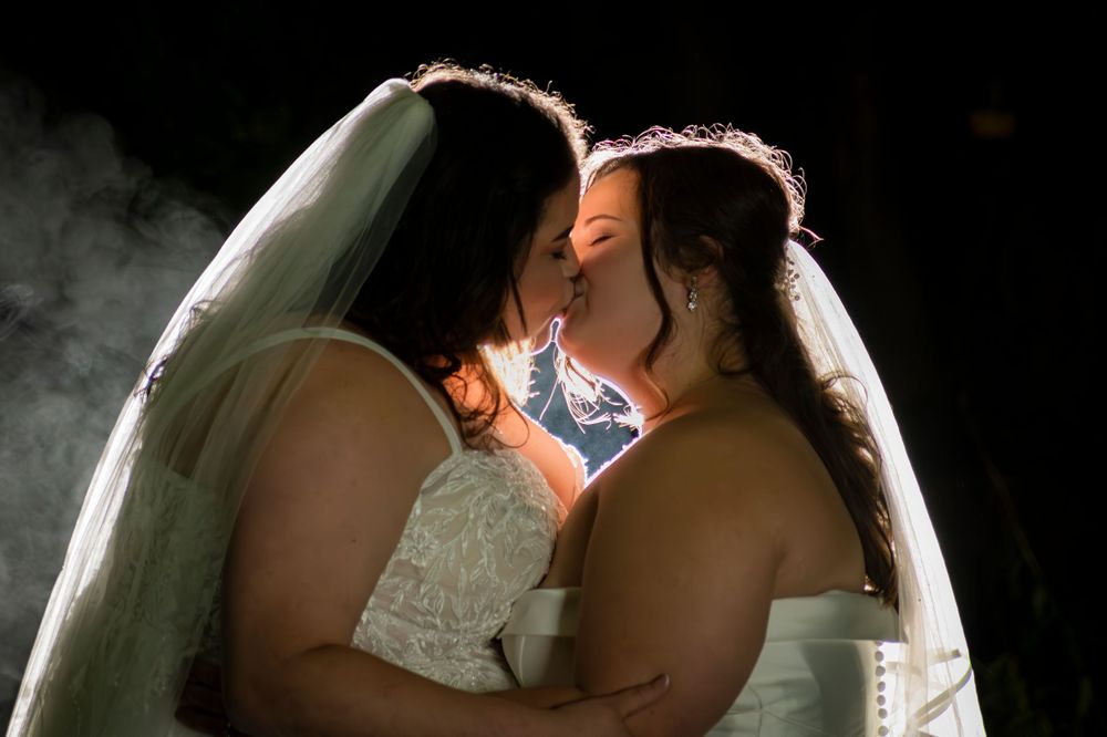 Two brides kiss against a smokey background at Cockliffe Hall, Nottinghamshire. Wedding Photography