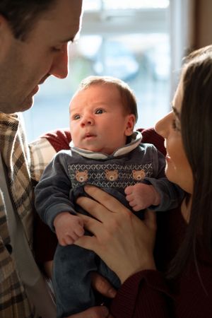 A tender family moment with parents cradling their newborn baby in a series of intimate poses.