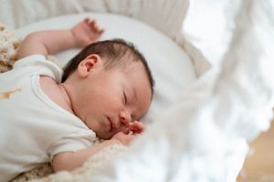 Sleeping newborn peacefully resting on white bedding.