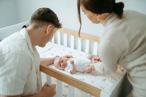 Tender moments as parents watch their baby in a white crib.