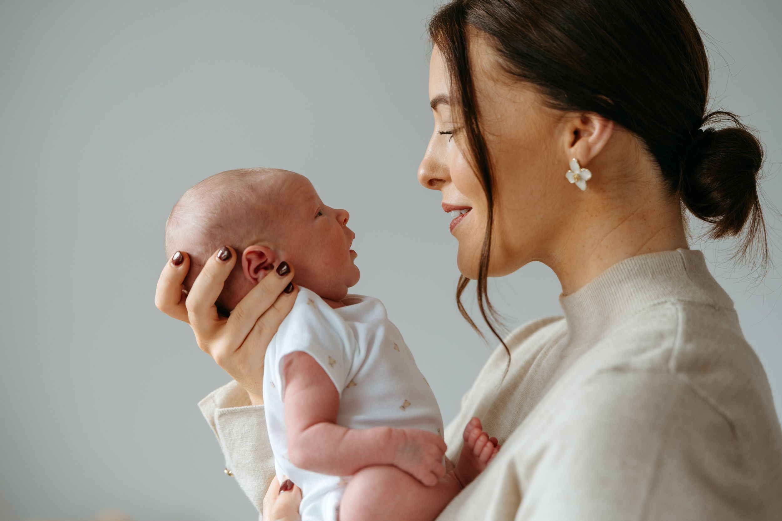 Intimate series of tender moments between parents and their newborn baby in soft, neutral tones.