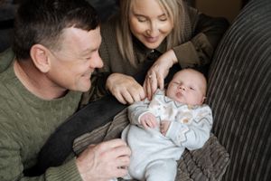 Family sharing tender moments with their newborn baby on a couch.