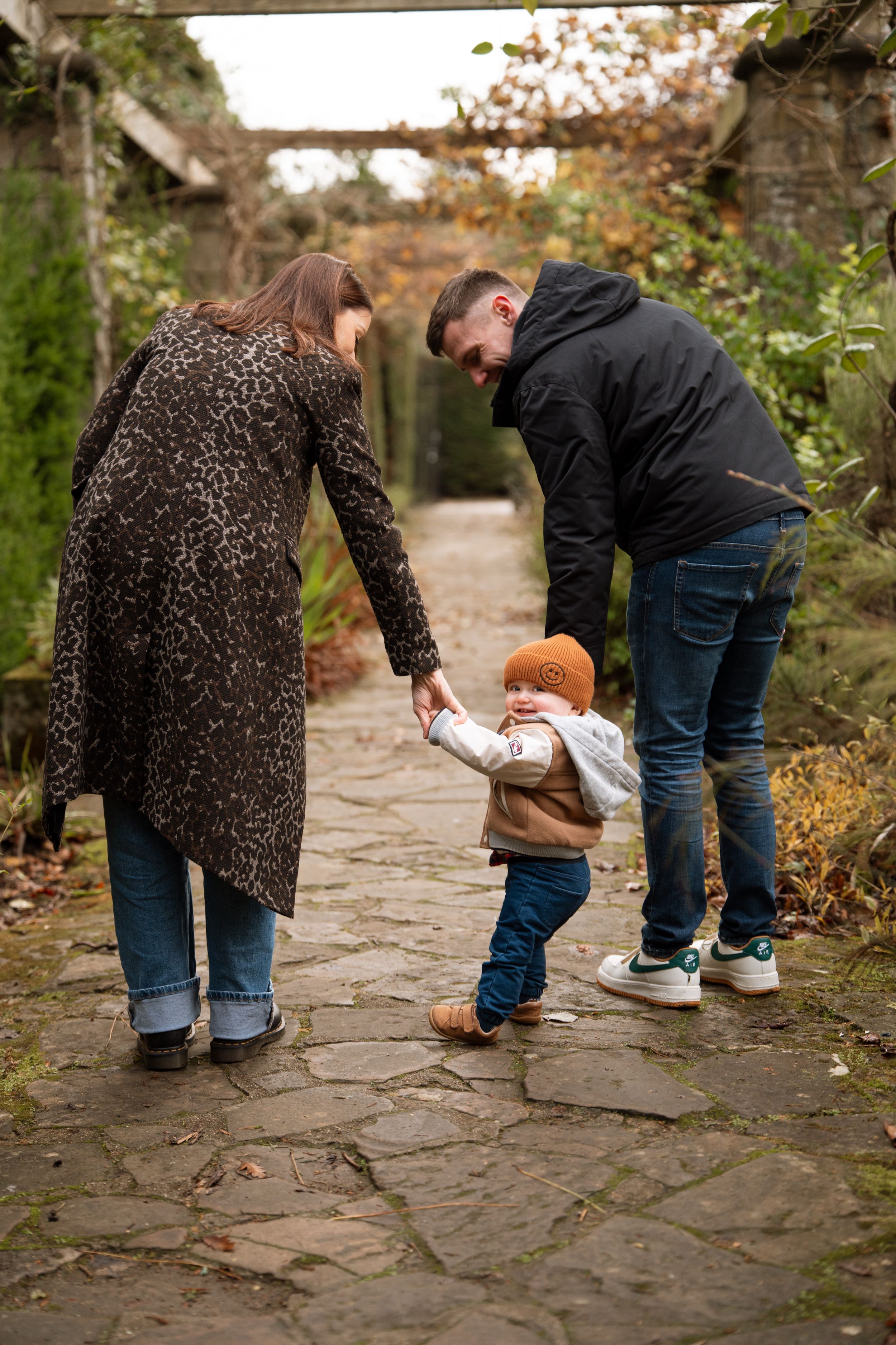 Family walking together on stone path during autumn day.