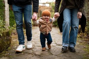 Close-up of family's feet walking together on outdoor stone pathway.