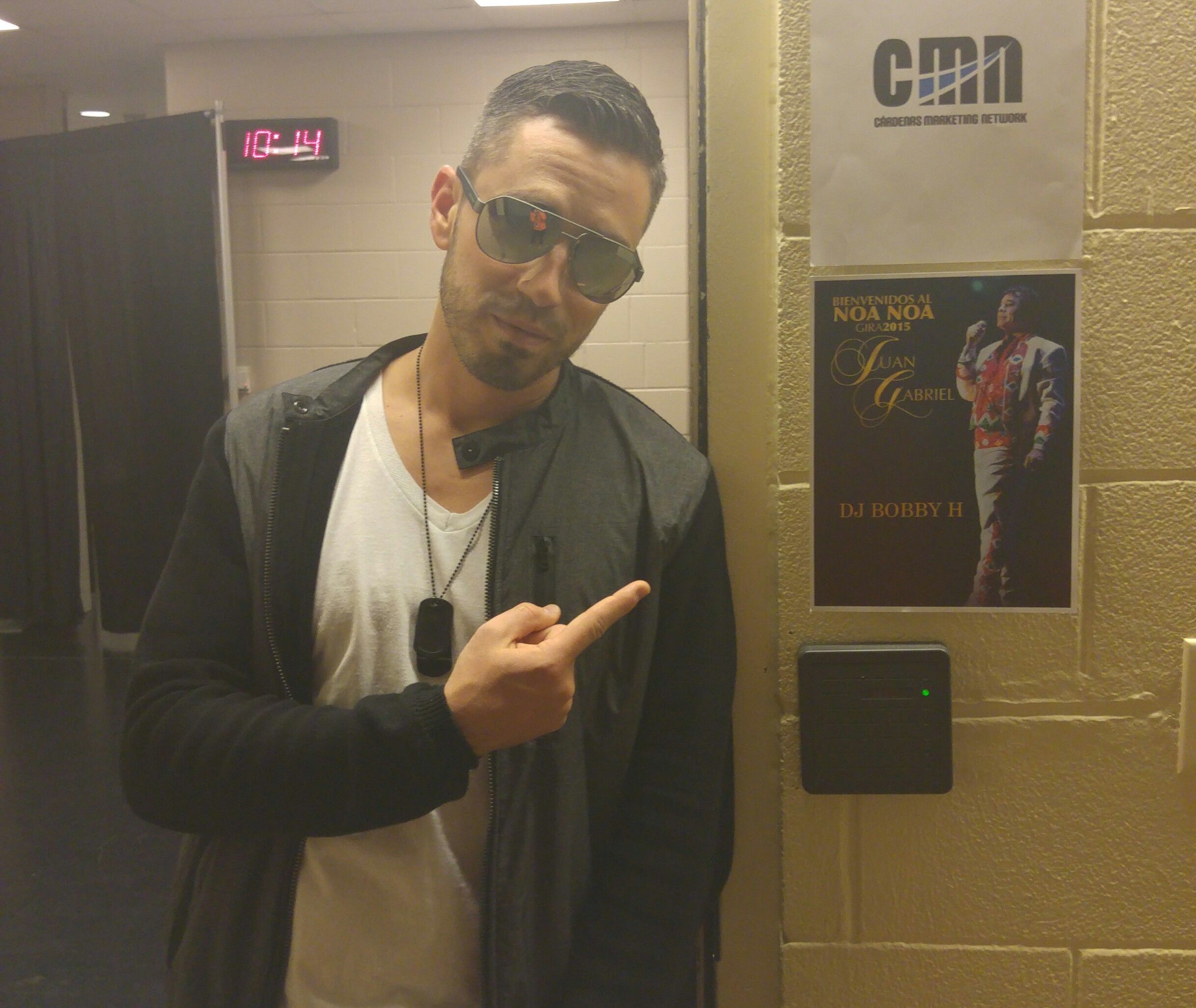 Multiple photos show someone posing and making gestures against a white cinderblock wall with posters in the background.