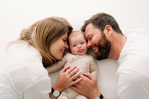 Mama en papa knuffelen hun baby tijdens een babyshoot in Edegem nabij Antwerpen