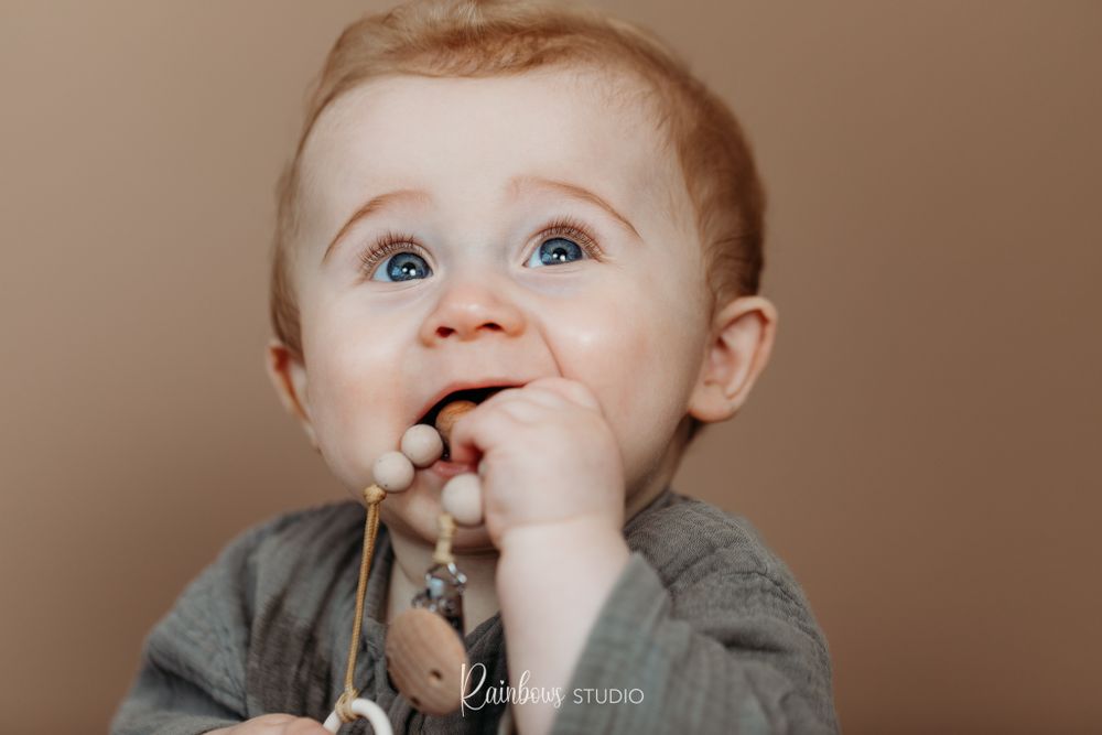 Baby die zijn tut koord in zijn mond heeft en wat omhoog kijkt