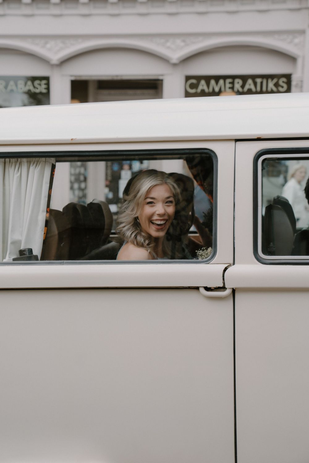 Joyful passenger laughing through window of vintage Cameratiks van.