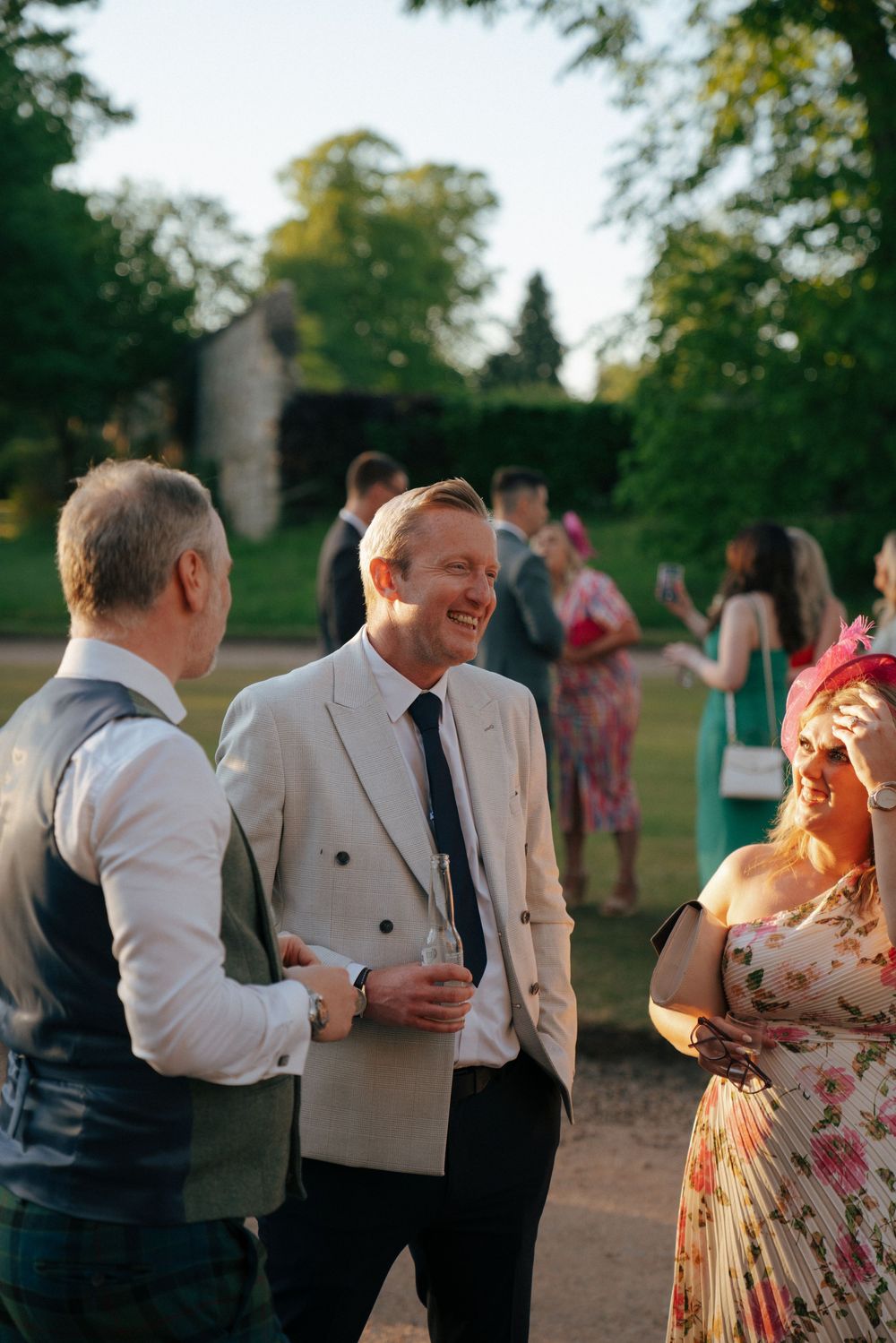 Wedding guests enjoying conversation during outdoor reception in evening light.
