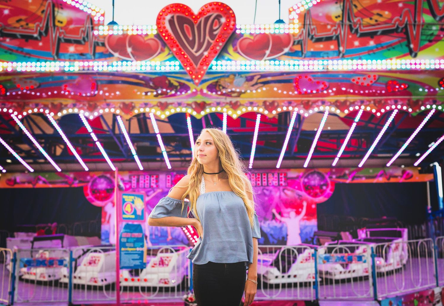A colorful carnival scene with neon heart and lights creating a vibrant fairground atmosphere.