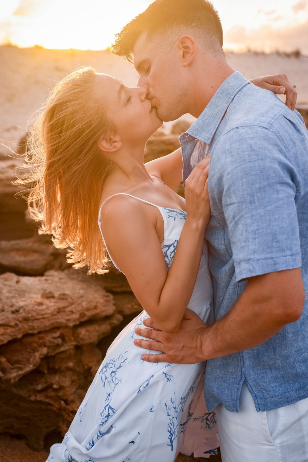 A tender embrace captured during golden hour on coastal rocks.