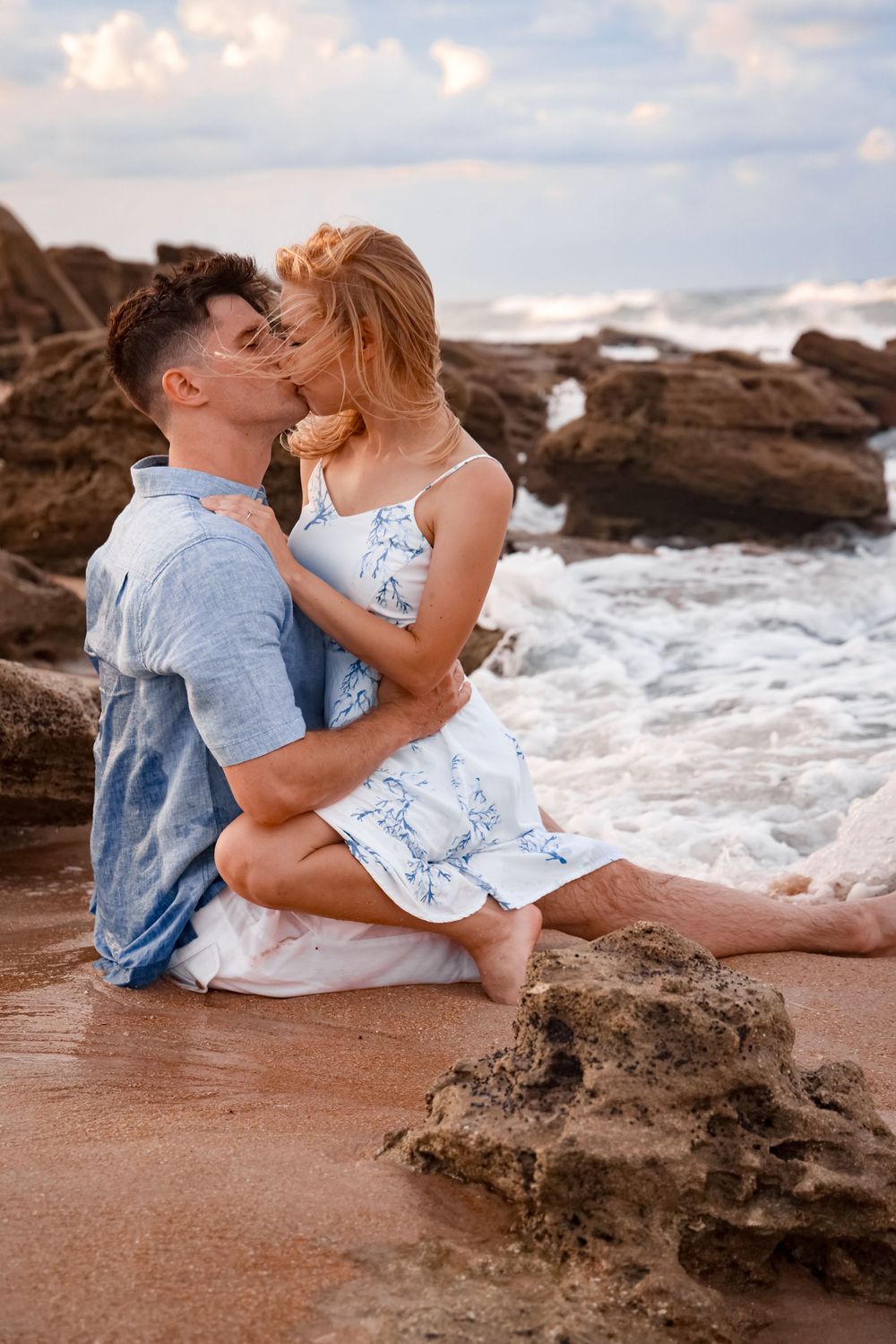 Intimate beach portrait of couple on coastal rocks at sunset.
