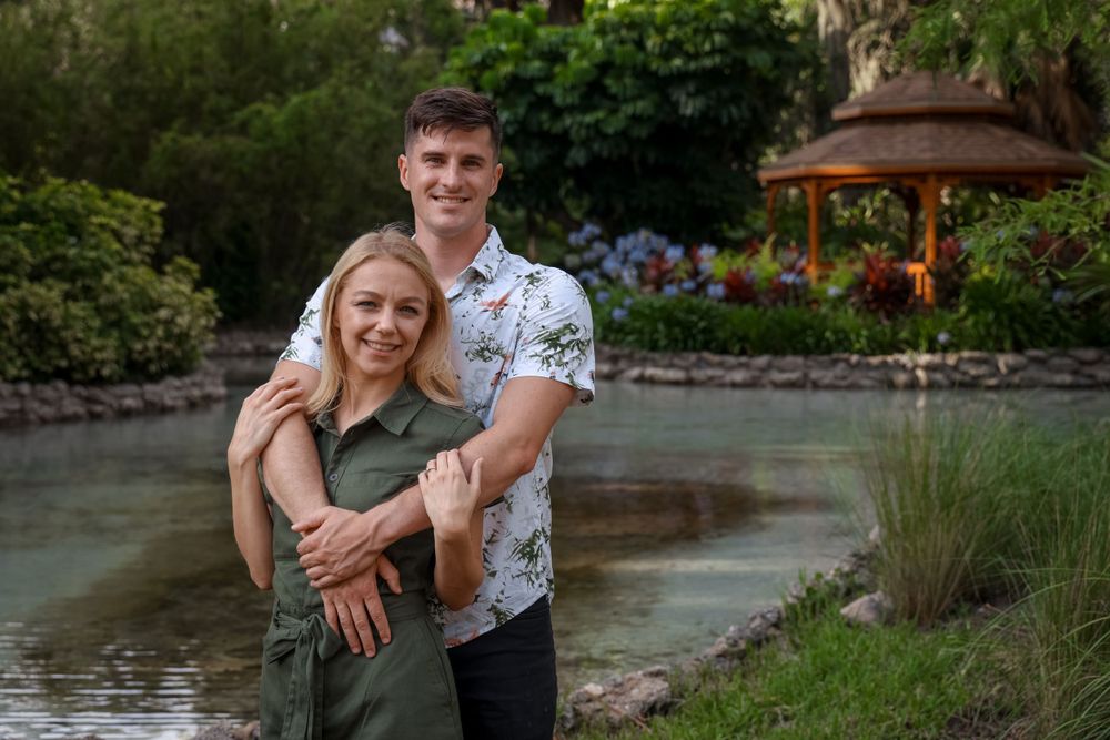 A romantic embrace by a serene pond in a garden setting.
