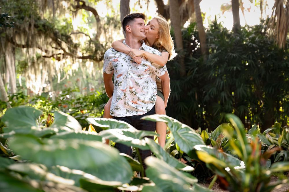A romantic moment captured in a lush tropical garden with Spanish moss and palm fronds surrounding the couple.