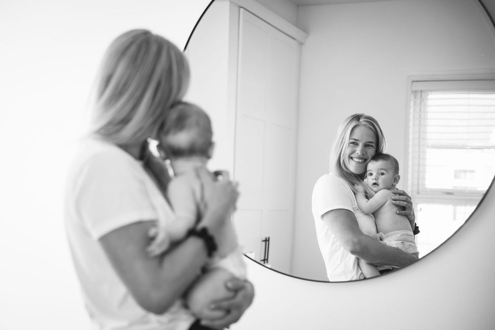 Tender reflection of parent and baby in bathroom mirror.