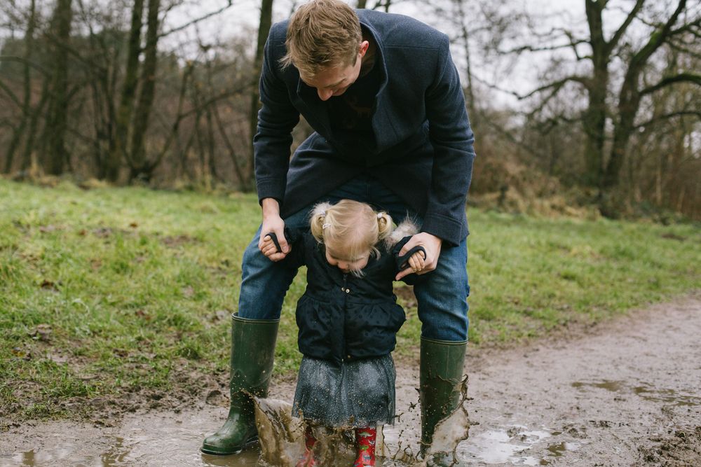 Parent and child wearing rainboots exploring outdoors on a wet trail.